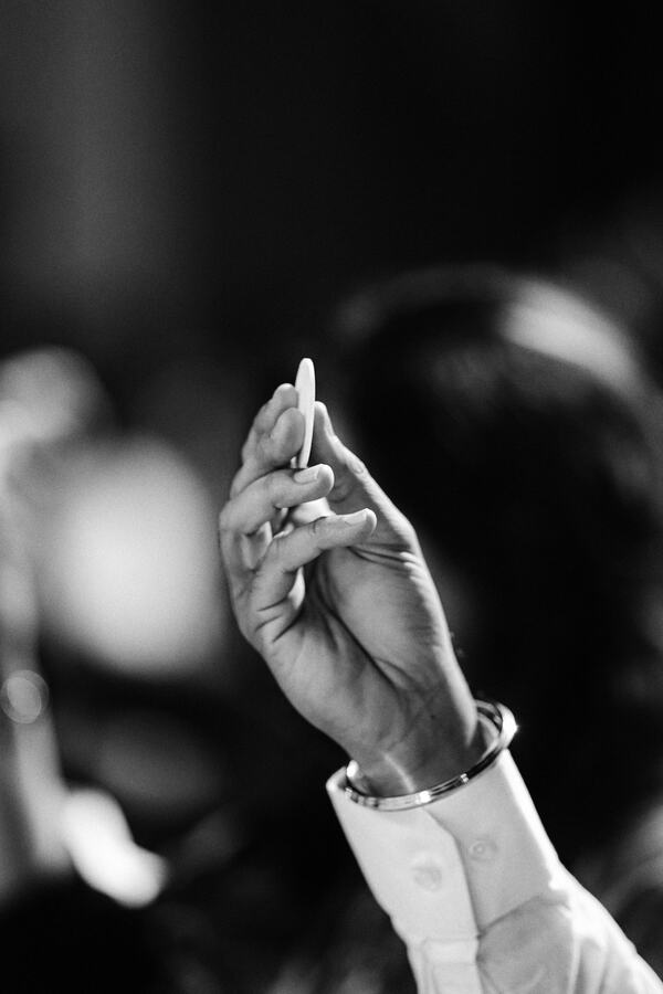 A bidder's raised hand holding a paddle, photographed in black and white